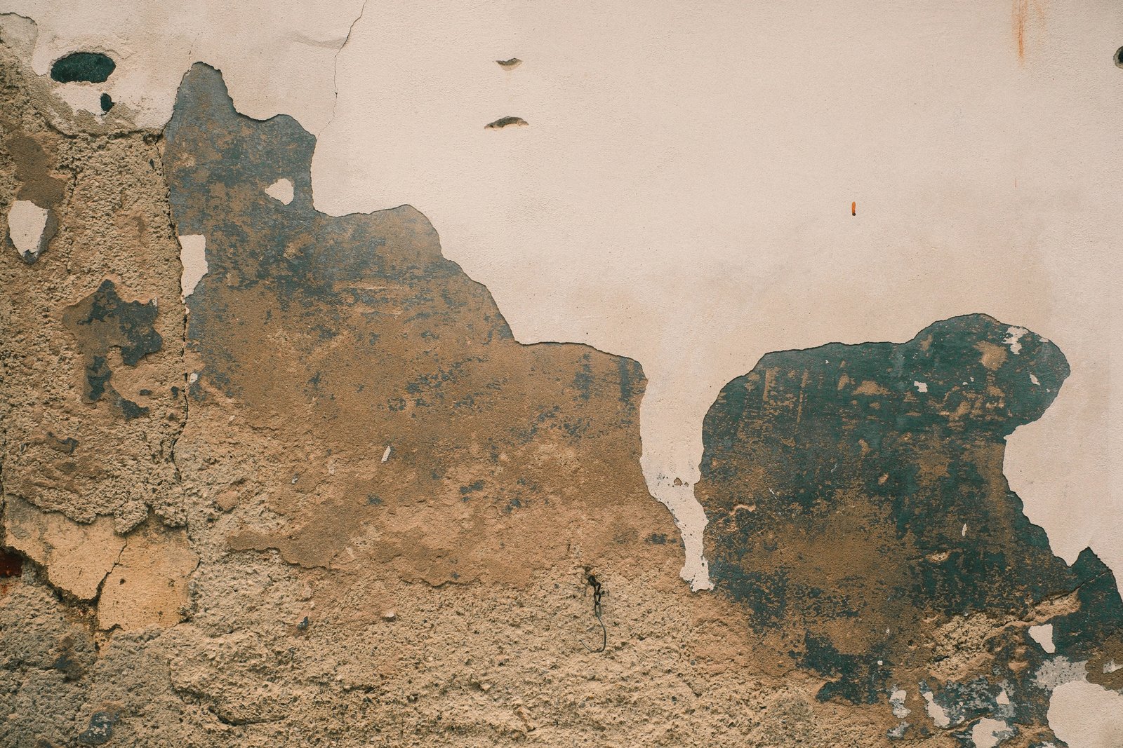 Wand mit abblätternder Putzschicht unter frischer Farbe