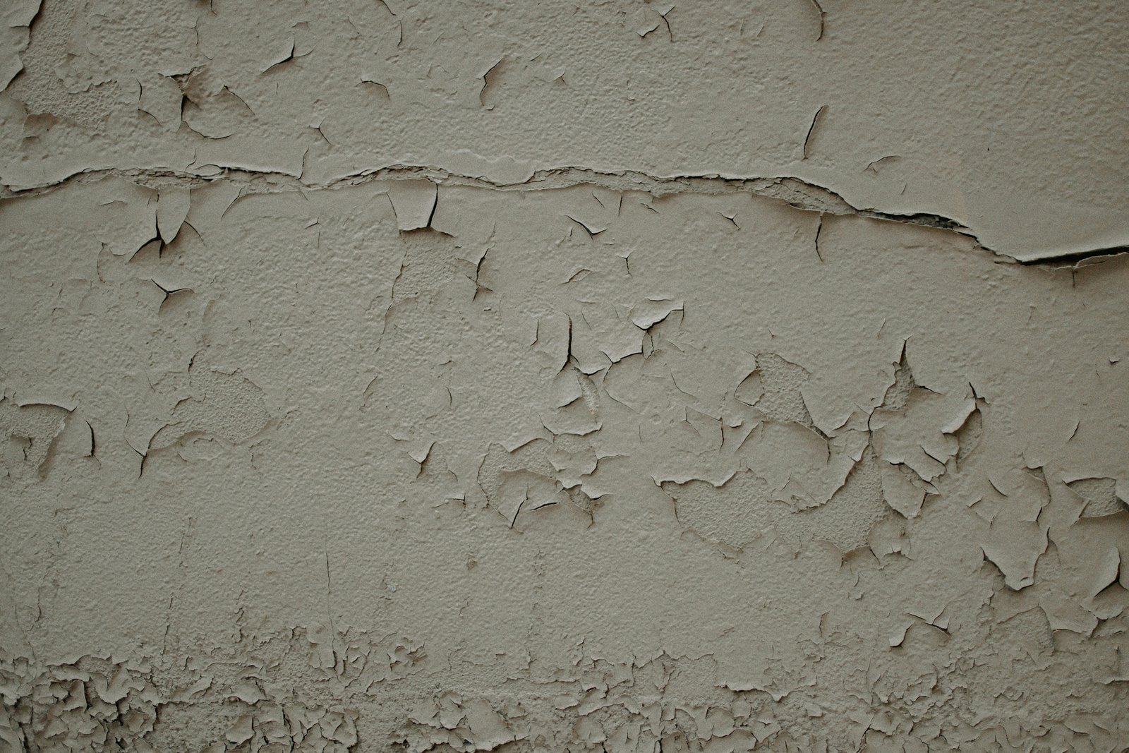 Wand mit teilweise gelöster Tapete und bröckelndem Putz darunter
