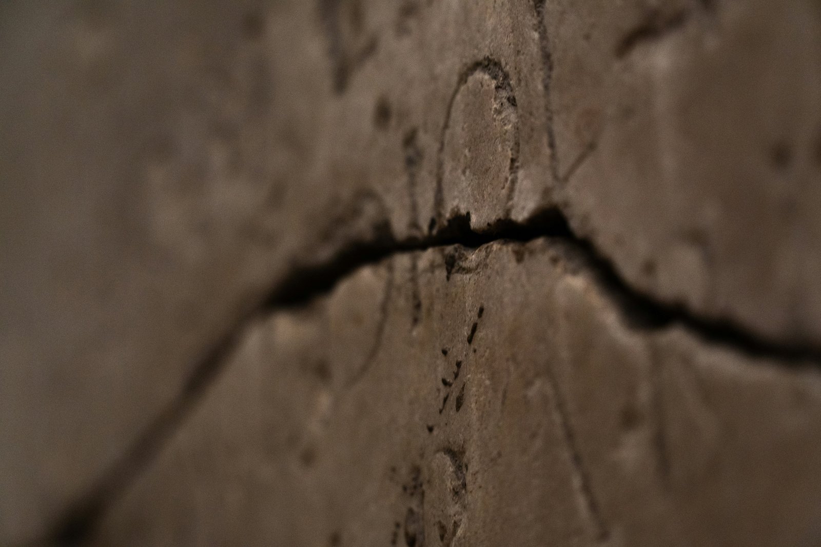 Innenwand mit mehreren bröckelnden Putzstellen und rauer Oberfläche