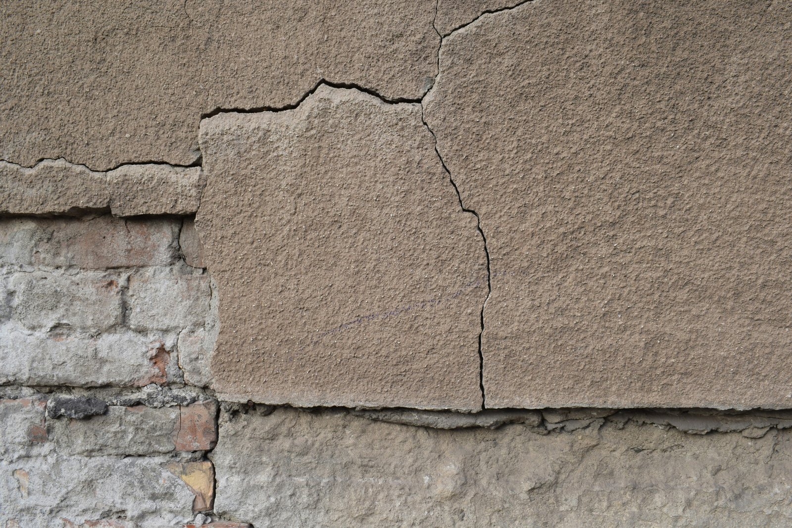 Wand mit teilweise gelöstem Putz und sichtbarem Mauerwerk