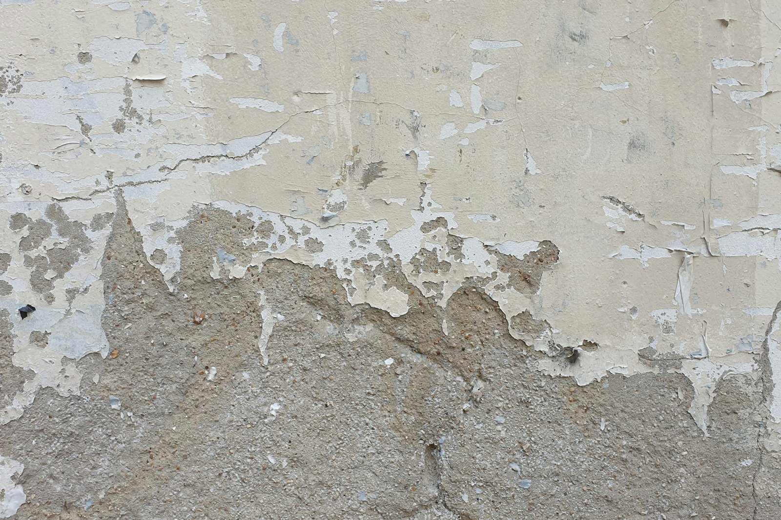 Wand mit verschiedenen beschädigten Putzstellen und ungleichmäßiger Oberfläche